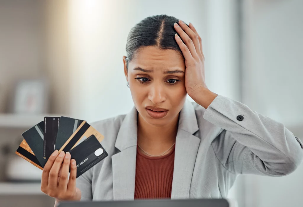 Businesswoman holding several credit cards, touching forehead — stressed about credit card lawsuits and bankruptcy options.